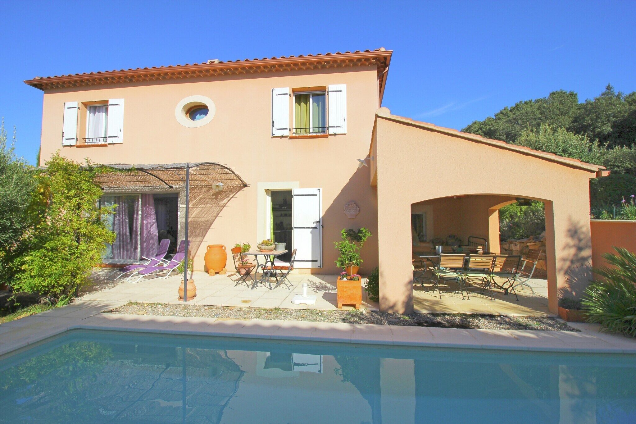 A two-story house with a swimming pool, outdoor seating, and a covered patio area.