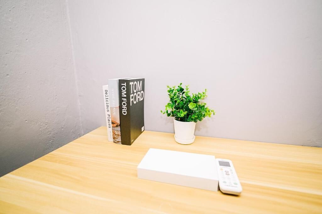 Un libro titulado 'Tom Ford' y una planta en maceta sobre una mesa de madera.