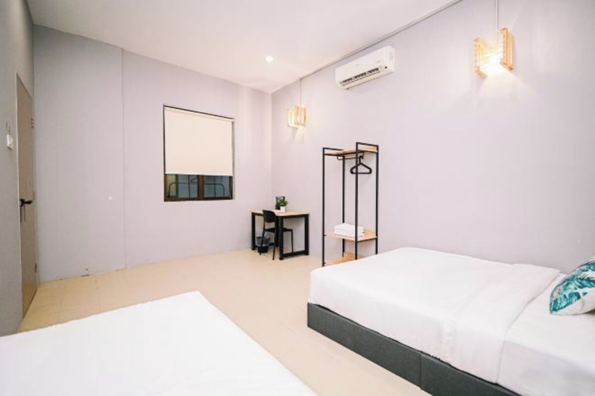 Ein modernes Schlafzimmer mit einem großen Bett, einem Schreibtisch und einem Stuhl. An der Wand hängt ein Spiegel und es befindet sich eine Klimaanlage im Raum.