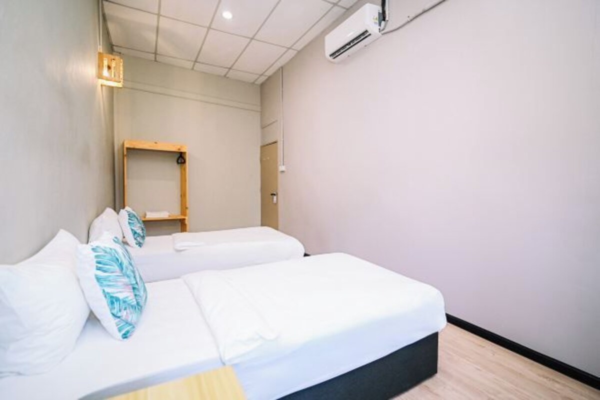 Ein Hotelzimmer mit zwei Einzelbetten, einer Holzablage und einer Wand-Klimaanlage.
