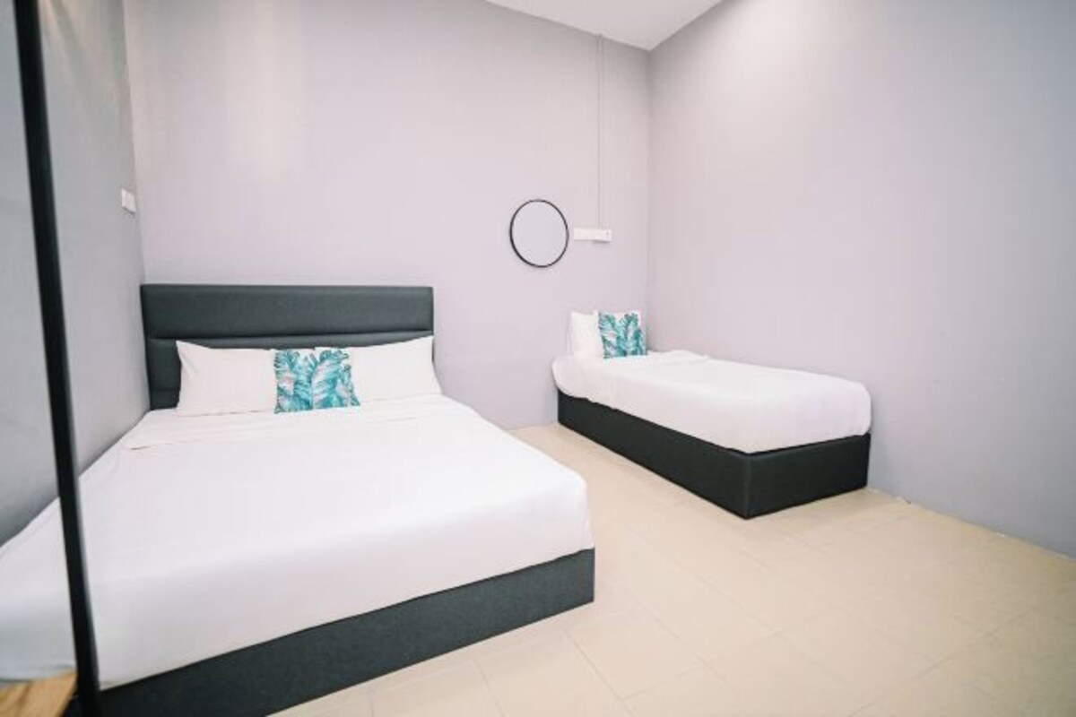 Een slaapkamer met twee bedden, waarvan één groter en één kleiner, beide met wit beddengoed en zwarte hoofdeinden.