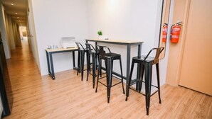 Une petite cuisine moderne, avec un plancher en bois, un comptoir blanc et des tabourets de bar noirs.