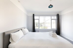 Une chambre d’hôtel avec un grand lit, une fenêtre avec des rideaux et un luminaire au plafond.