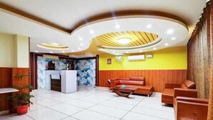 A lobby with a reception desk, seating area, and a decorative ceiling. - Hotel Vibe Blue (Noida)