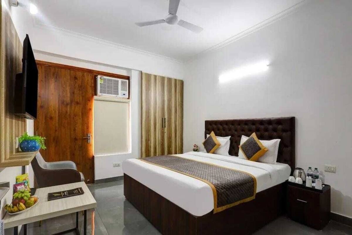 A hotel room with a bed, a desk with a chair, a TV, and a wardrobe.