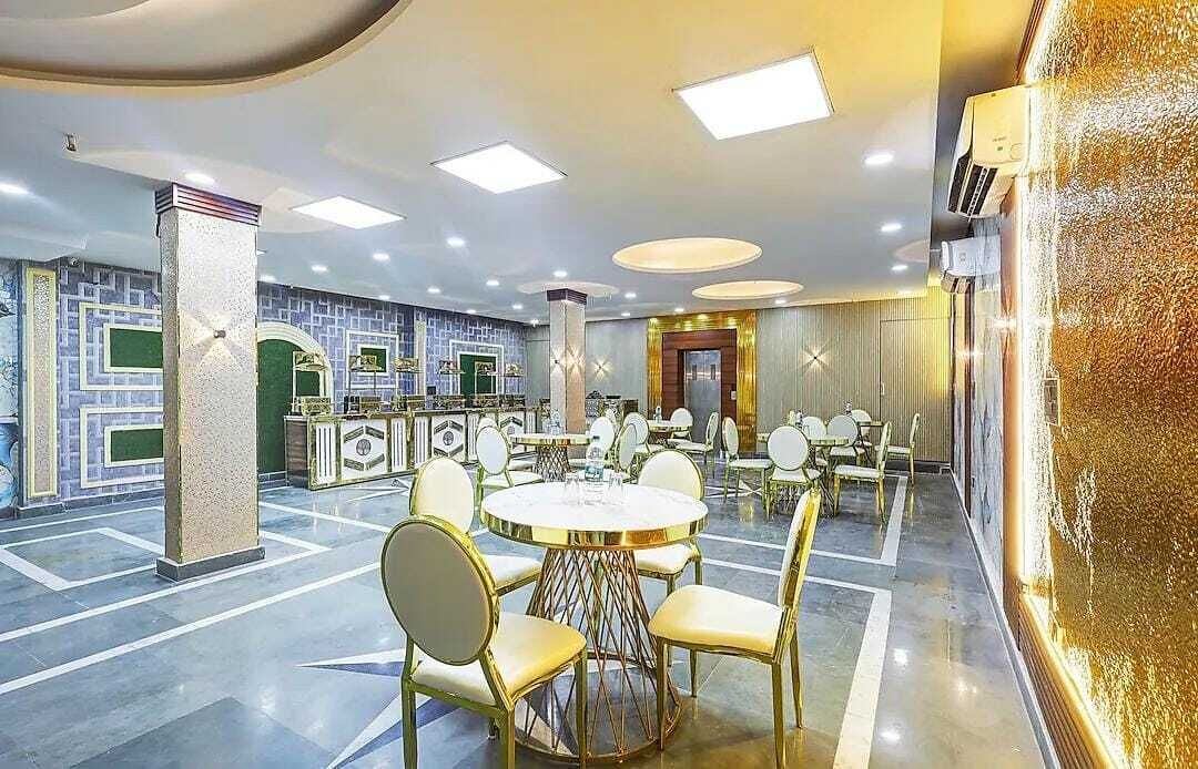 Un hall d’hôtel spacieux, avec une grande table ronde au centre, entourée de chaises, un comptoir de réception et un mur décoratif.