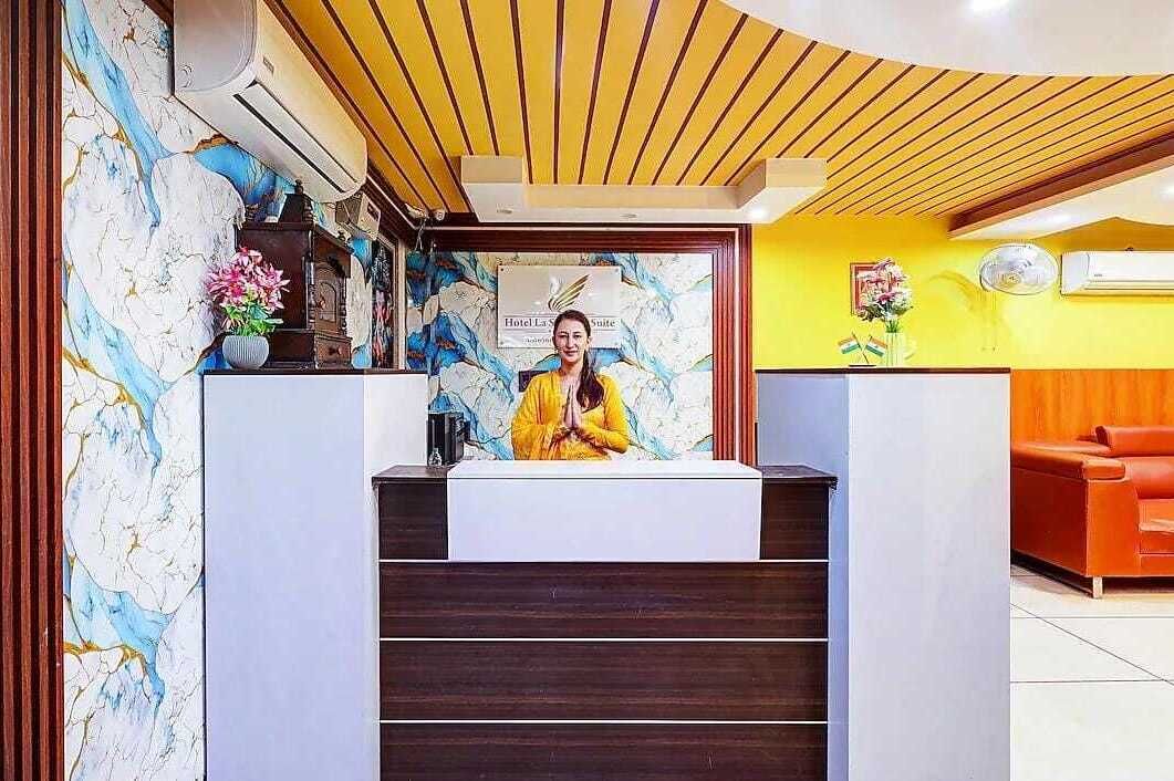 En hotelreception med en receptionist, en marmorvæg og et træloft.