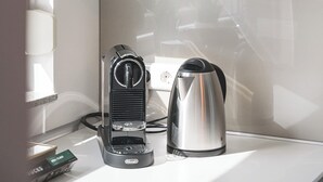 A kitchen with a toaster, a kettle, and a potted plant on the counter.