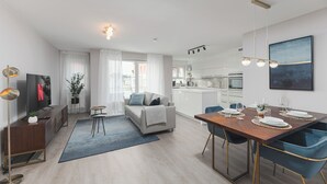A modern living room with a sofa, coffee table, and dining area with chairs and a table set for four.