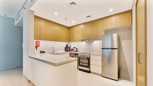 Eine moderne Küche mit Kochinsel, Backofen und Edelstahlkühlschrank.