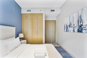 Ein modernes Hotelzimmer mit einem großen Bett, einem Holzschrank, einem Gemälde mit Segelbooten und einer blauen Akzentwand.