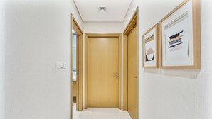 Ein Flur mit einer Holztür, weißen Wänden und gerahmten Kunstwerken.