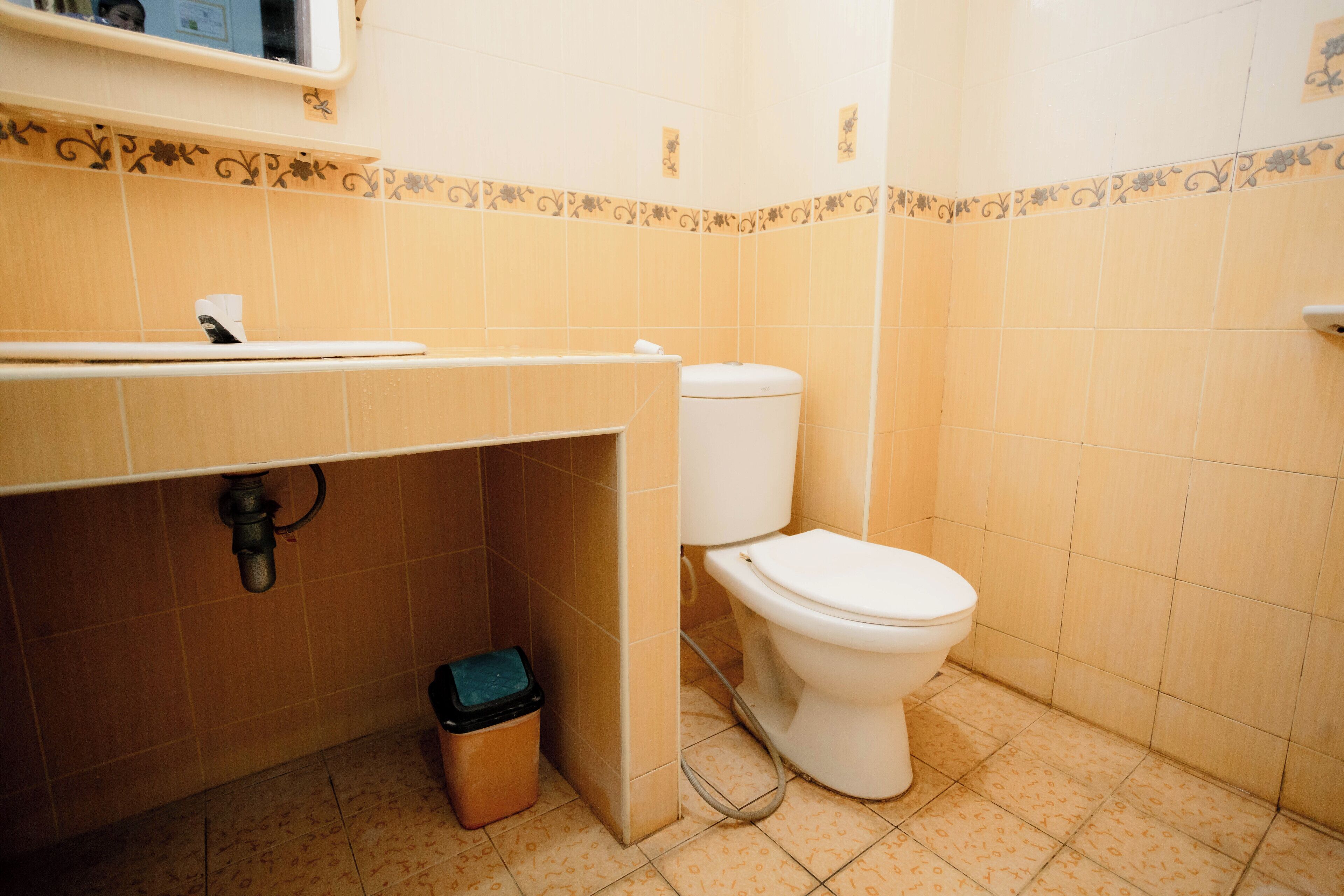 Un baño con inodoro, lavamanos y cubo de basura.