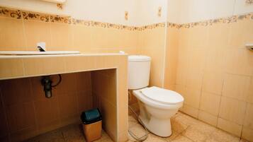 Un baño con inodoro, lavamanos y cubo de basura.