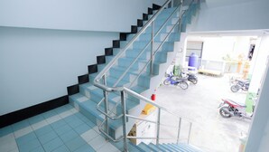 A staircase with metal railings leading to an outdoor area with parked motorcycles. - Thongkon Hotel (Surin)