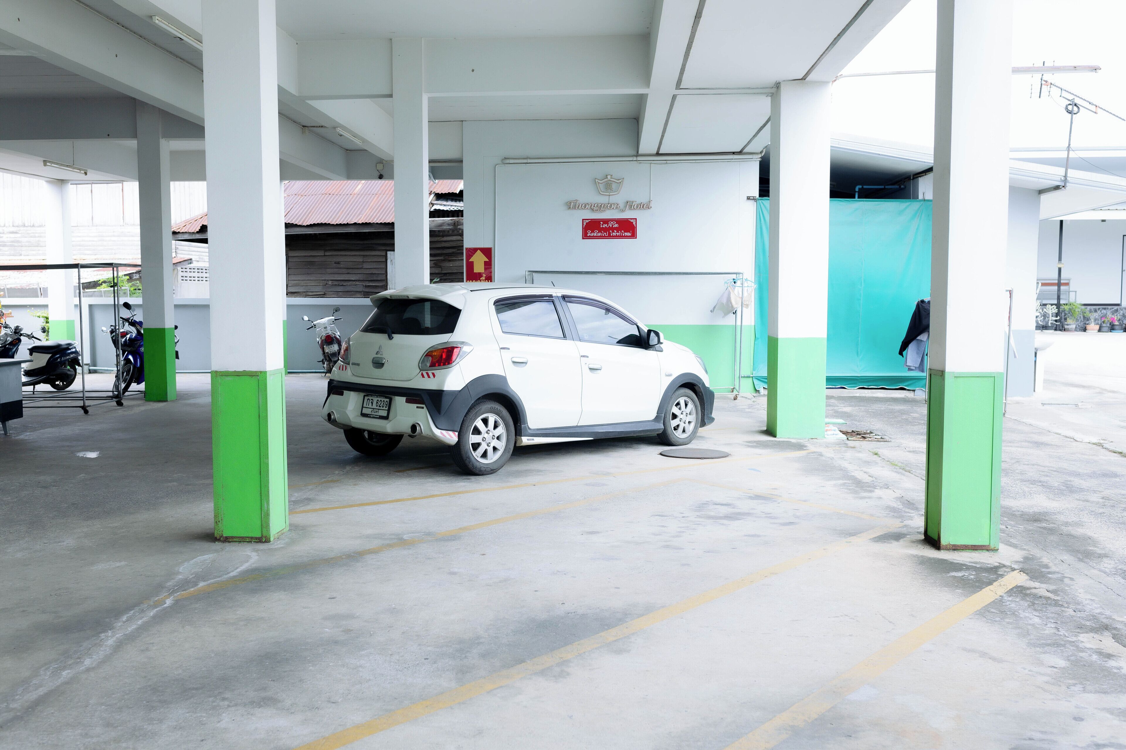 A parking area with a white car parked under a covered structure.