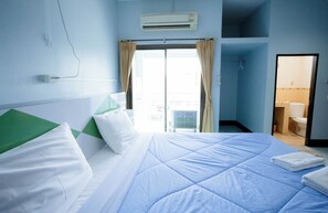 A hotel room with a bed, a window with curtains, an air conditioning unit, and a bathroom visible through the door. - Thongkon Hotel (Surin)