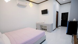 A modern bedroom with a bed, a desk with a chair, a TV, and a wardrobe. - Thongkon Hotel (Surin)