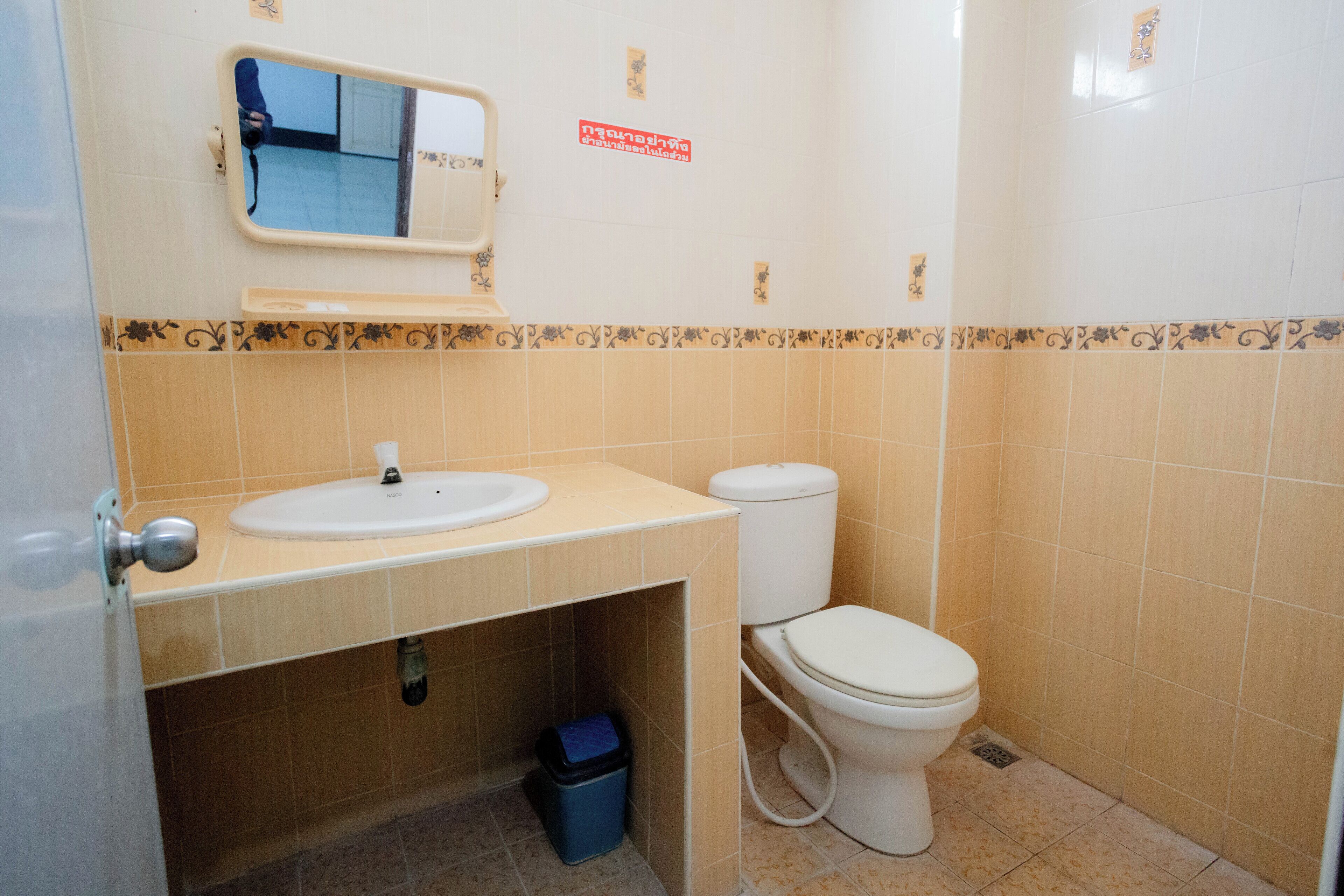 A bathroom with a sink, toilet, and a mirror.