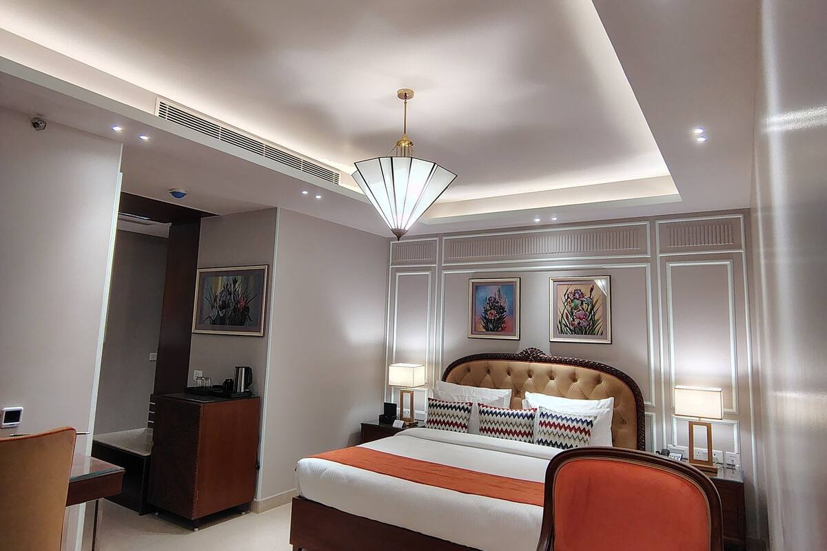 A hotel room with a large bed, a desk, a chair, and a small table.