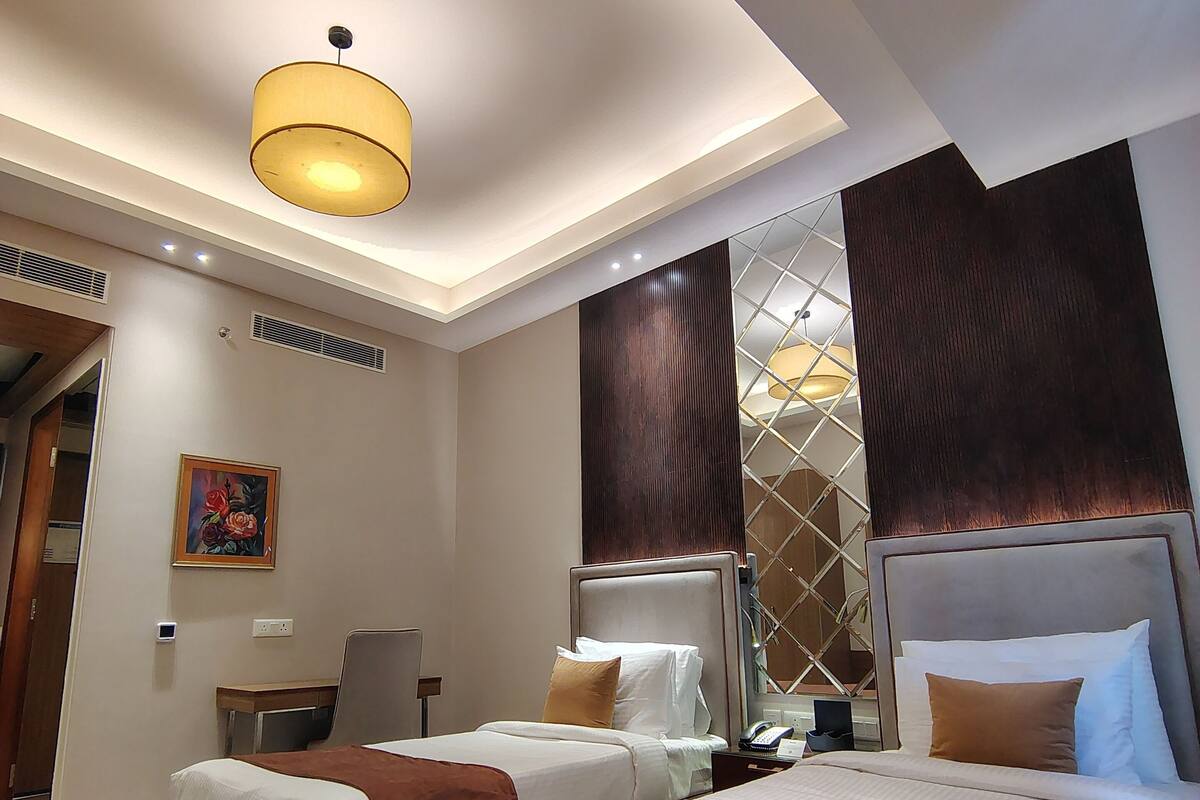 A modern hotel room with a large bed, two bedside tables, a desk, and a chair.