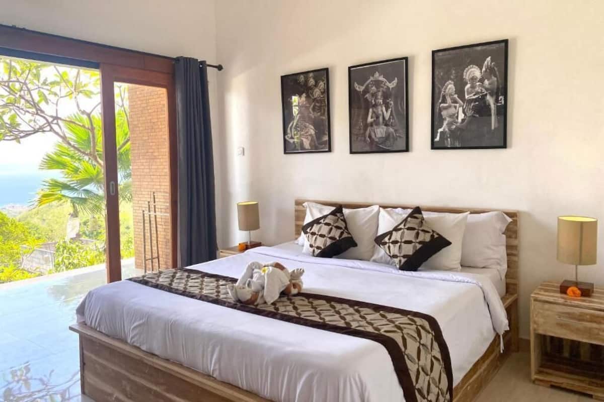 Habitación de hotel con una cama grande, vistas al exterior y tres cuadros en la pared.