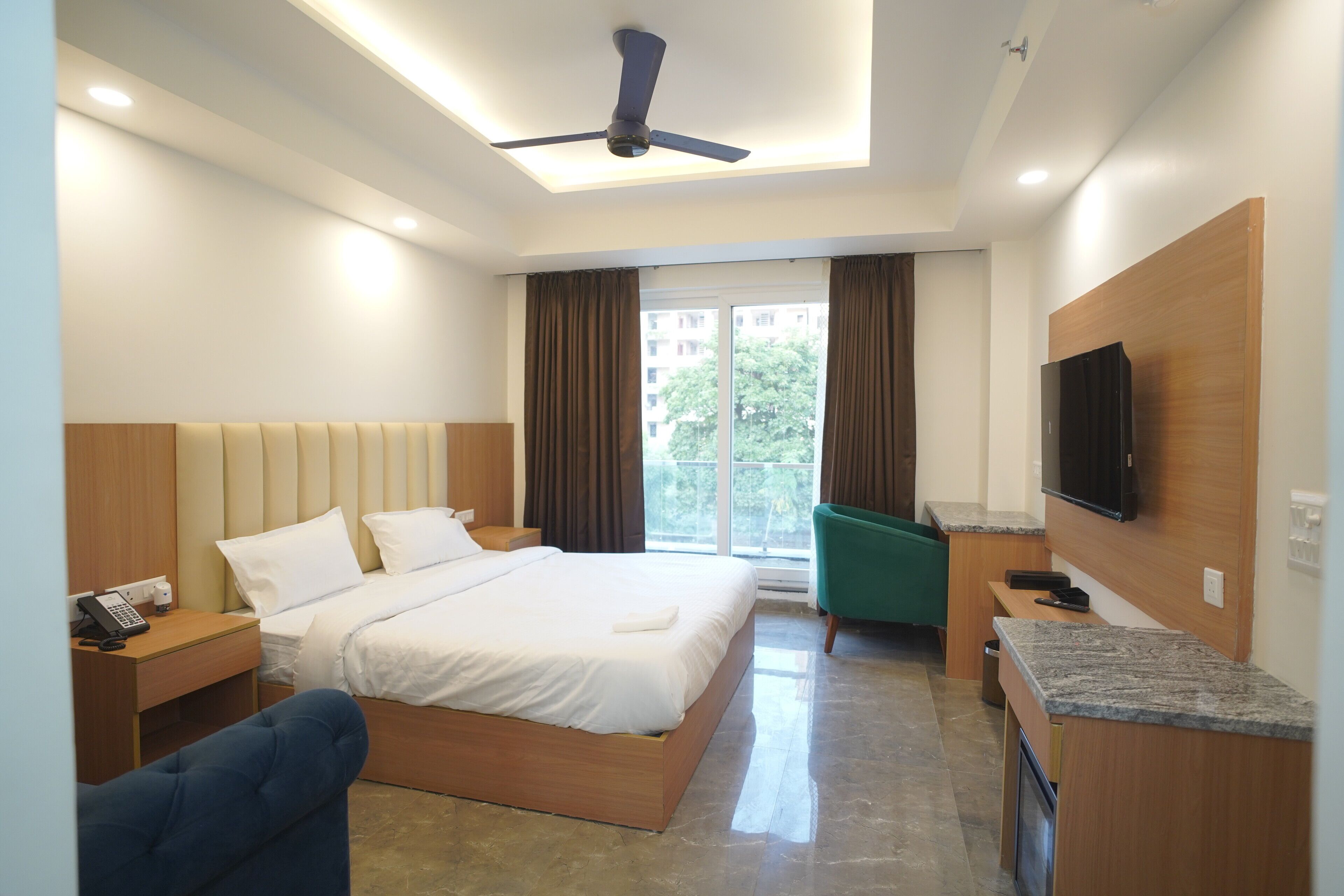 Habitació d'hotel moderna amb llit, escriptori, cadira, televisió i balcó amb cortines.