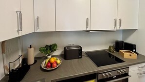 Eine moderne Küche mit weißen Schränken, einer schwarzen Arbeitsplatte, einem Toaster, einem Wasserkocher und einer Obstschale.