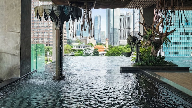 Un élément décoratif aquatique intérieur au design moderne, offrant une vue sur le paysage urbain et agrémenté d’une sculpture en forme d’arbre.