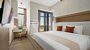 Une chambre d’hôtel moderne avec un grand lit, un bureau avec un ordinateur portable et un téléviseur affichant « NETFLIX ».