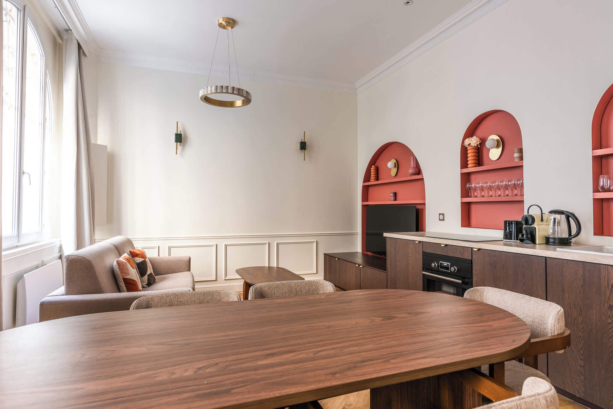 Una cocina moderna con una mesa de comedor de madera, armarios empotrados y un diseño en arco rojo en la pared.
