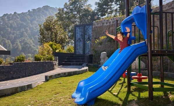 Une aire de jeux avec un toboggan bleu et des structures d’escalade.