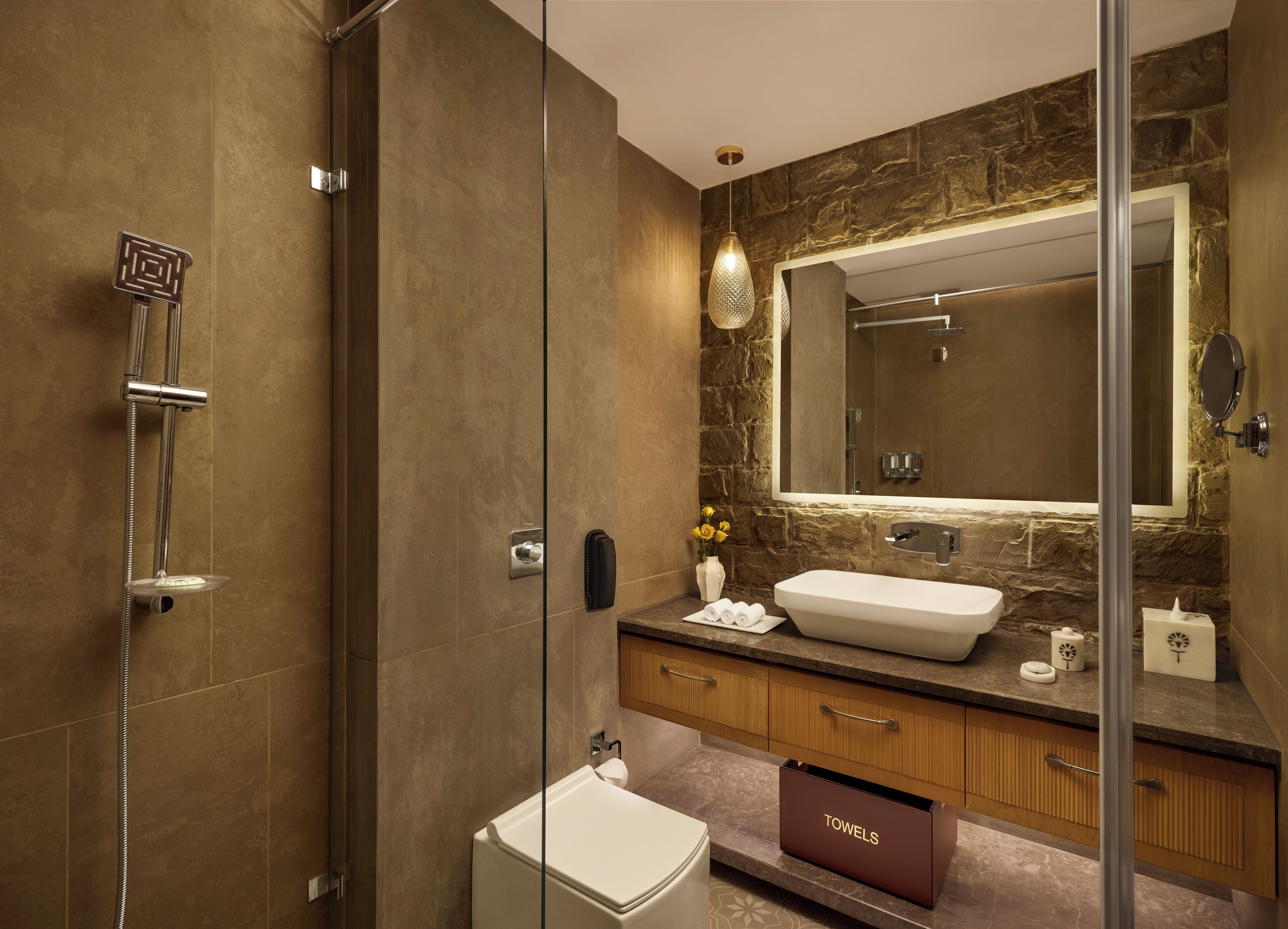 A modern bathroom with a glass-enclosed shower, a large mirror, a sink, and a toilet.
