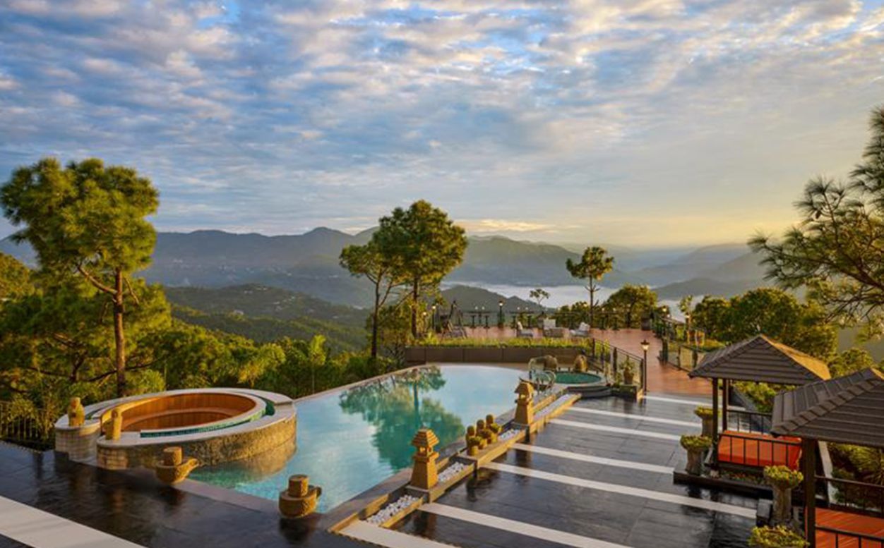 A pool area with a view of mountains, surrounded by trees and a gazebo.
