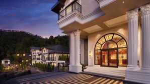 Una imponente entrada de hotel con un gran arco, columnas y un camino bien iluminado que conduce a la entrada.