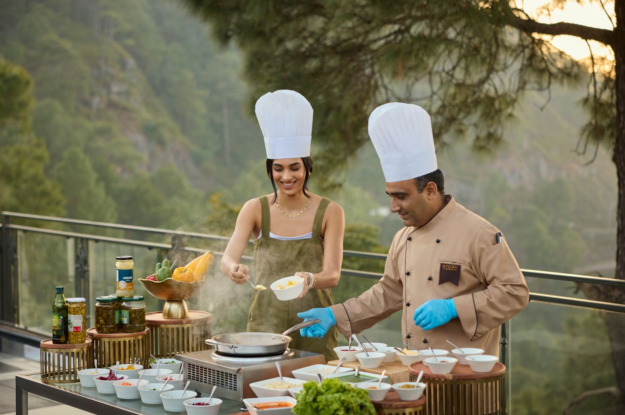 A chef preparing food outdoors with a scenic view in the background.