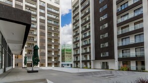 Un immeuble d’appartements moderne doté de nombreux balcons, d’un hall d’entrée abrité et offrant une vue sur un ciel dégagé.