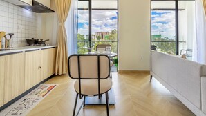 Une cuisine moderne avec un coin repas, de grandes fenêtres et une vue sur les immeubles.