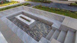 Un espace extérieur moderne agrémenté d’un bac à plantes rectangulaire et d’un sol carrelé à motifs.