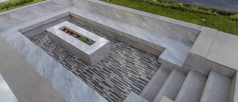 Un espacio exterior moderno con un macetero rectangular y un suelo de baldosas con diseño.