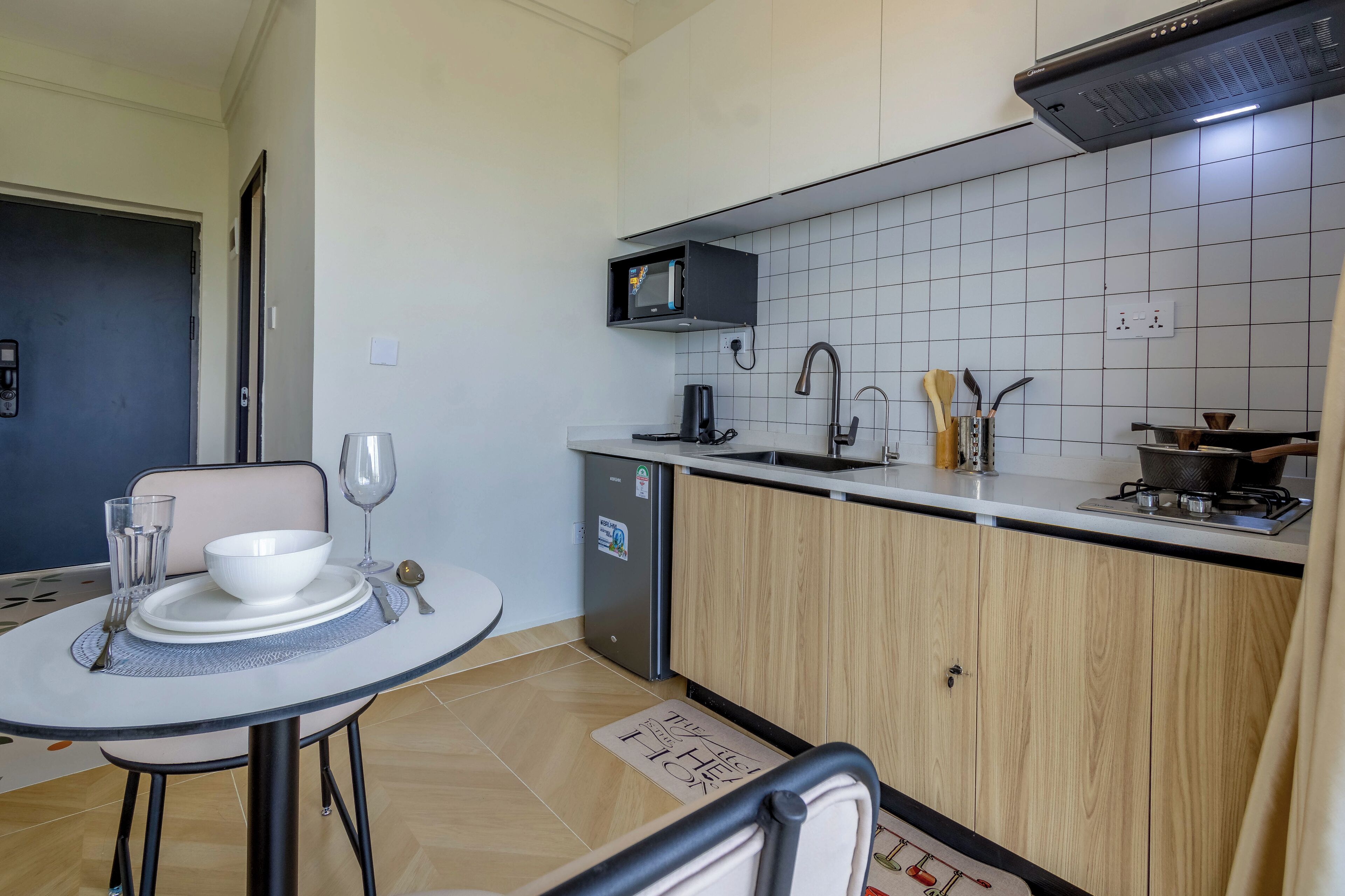 A compact kitchen with a microwave, sink, and small refrigerator.