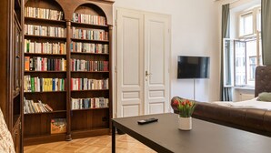 Uma sala de estar com uma grande estante de livros, uma TV de tela plana, um sofá e uma mesa de centro.
