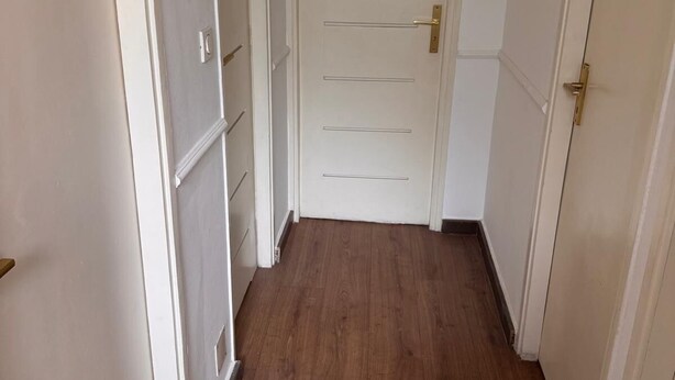 Un couloir doté d’un plancher en bois et de portes blanches.