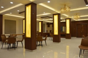 A modern hotel lobby with wooden pillars, a chandelier, and a reception desk. - Hotel Mountain Paradise (Abu Road)
