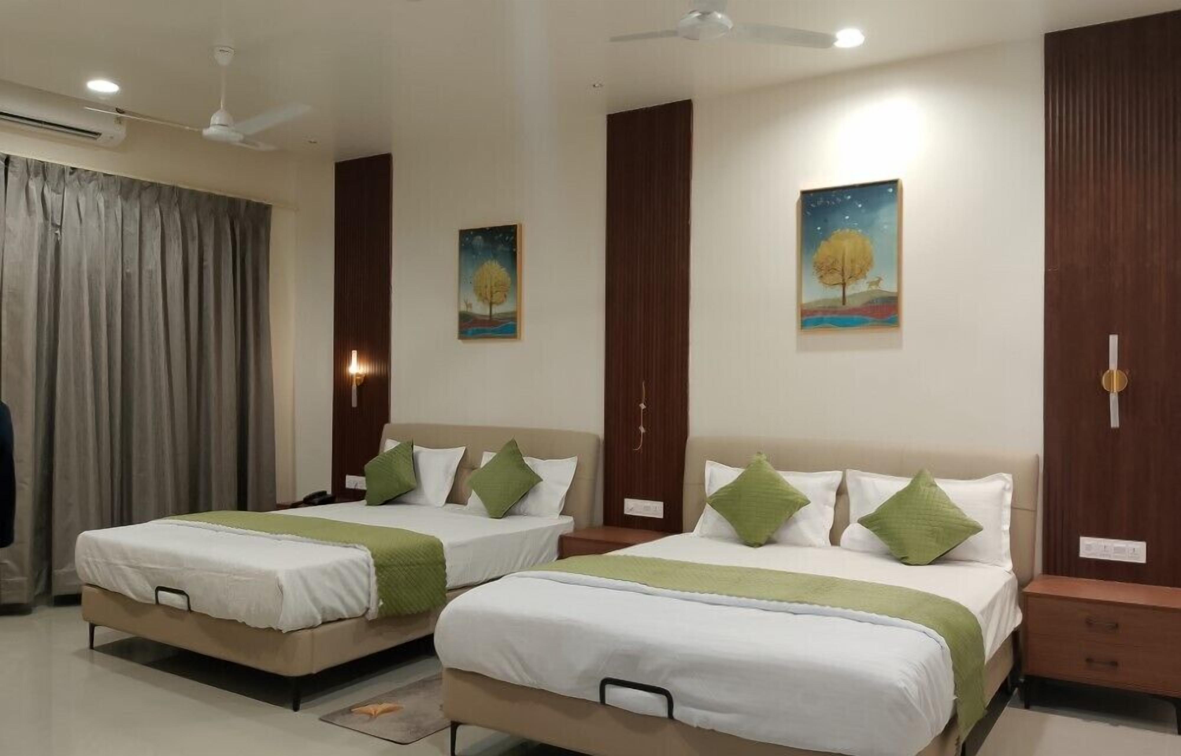 A hotel room with two beds, a ceiling fan, a painting on the wall, and a wooden wardrobe.