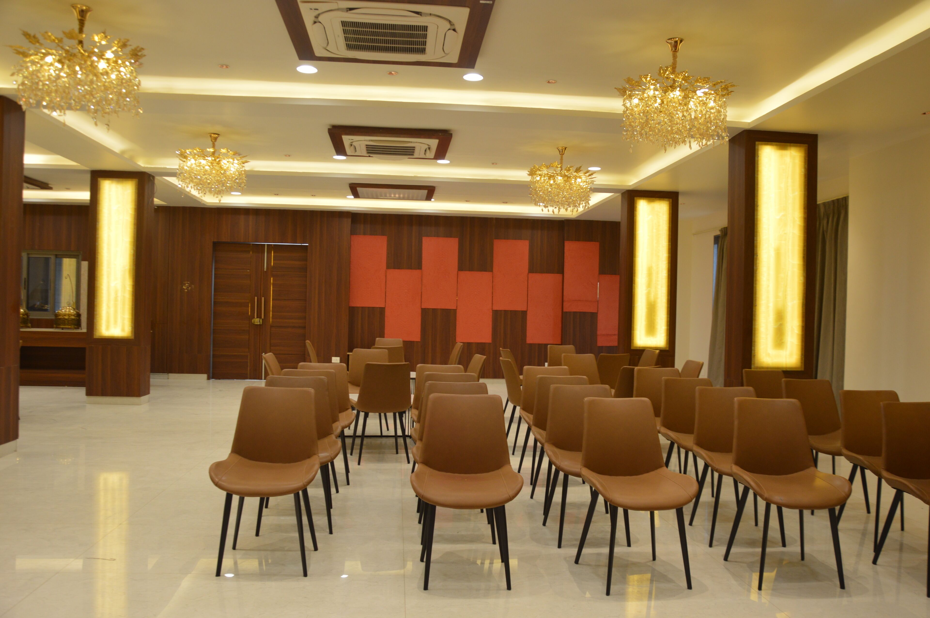 A conference room with rows of chairs, chandeliers, and wooden paneling.