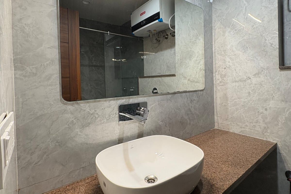 Een moderne badkamer met een rechthoekige spiegel, een wit wastafelmeubel en een handdoekhouder.
