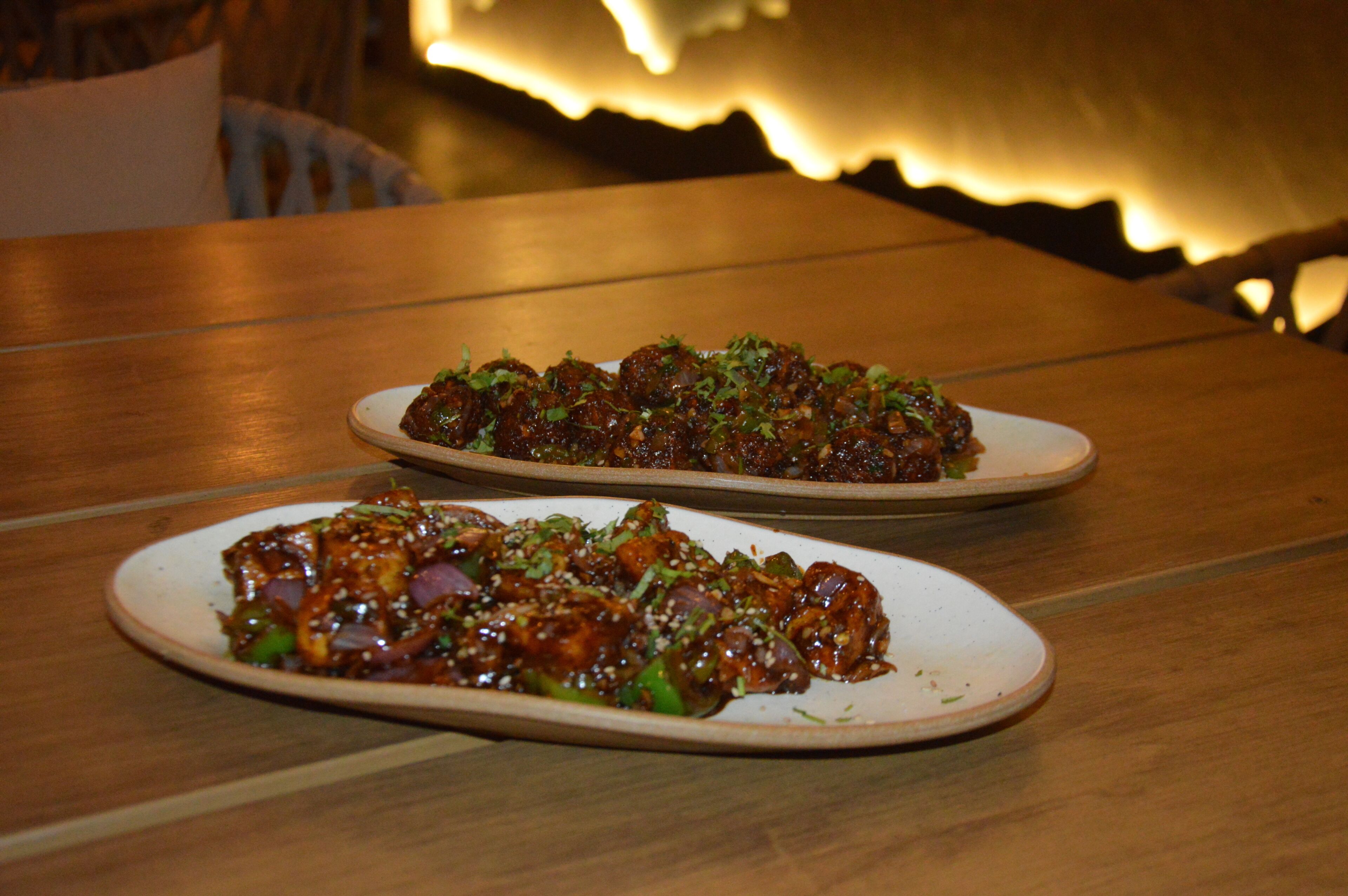 Two plates of food on a wooden table with a blurred background.