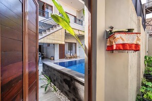 A modern house with a swimming pool, wooden doors, and a balcony with a railing. - Rumah Kodel Legian (Legian)