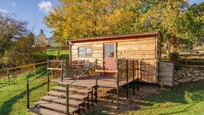 Une cabane en bois rustique, dotée d’une véranda, de marches et d’un espace clôturé.
